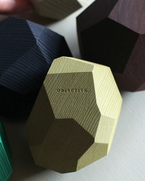 Hand holding geometric wooden coasters on a light surface